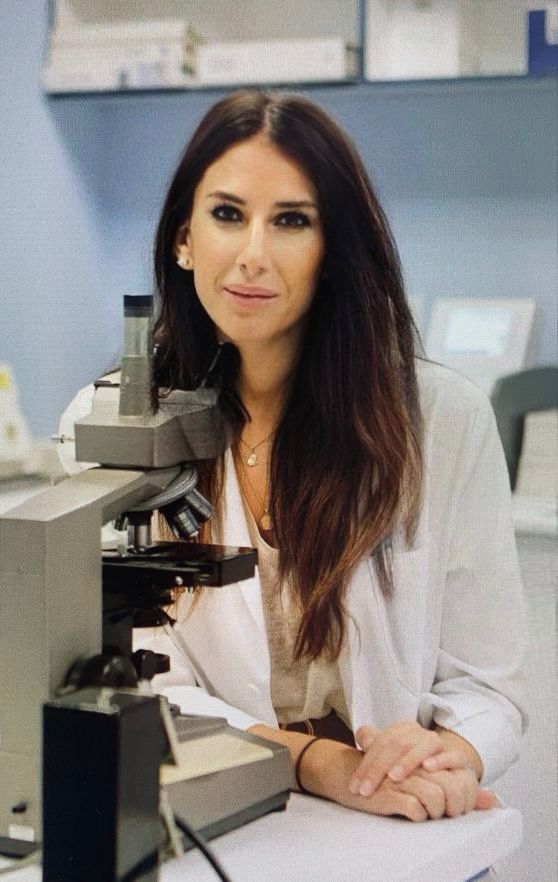 Mujer de bata blanca al lado de microscopio