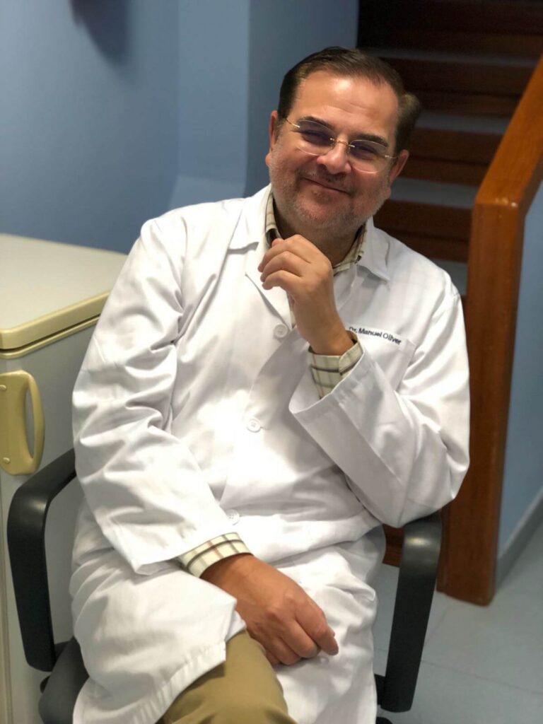 Dr. Manuel Oliver sonriente sentado en una silla
